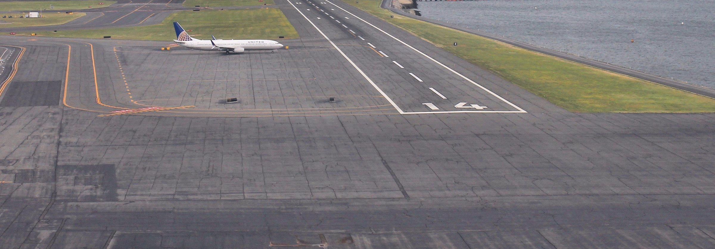 Runway 14 at Boston Logan International Airport, with a United Airlines jet holding short
